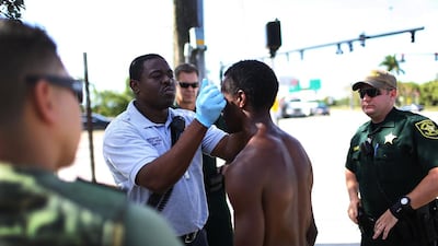 A paramedic takes the temperature of man suspected of being under the influence of flakka at Pompano Beach, Florida. Police officers surround the suspect in case he becomes violent. Joe Raedle / Getty Images