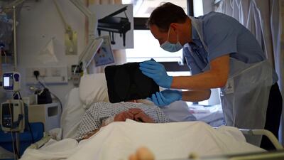 Chaplain David Anderson helps a patient communicate with his family, who are unable to visit due to coronavirus visiting restrictions, using the Zoom app on an iPad at the Royal Blackburn Teaching Hospital in Blackburn, north-west England on May 14. Hannah Mckay/ AFP / Pool