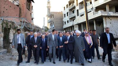 Syrian President Bashar Al Assad walking on a street alongside officials after performing the morning Eid Al Adha prayer at a mosque in a government-controlled area of Daraya. AFP PHOTO / HO / SANA