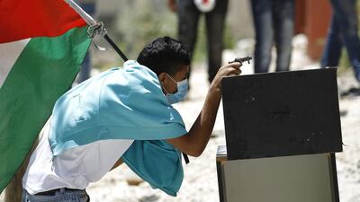 A Palestinian protester, holding the Palestinian flag, uses a toy gun during clashes with Israeli troops over the controversial Israeli barrier in Kfar Aqab near the West Bank city of Ramallah. Mohamad Torokman / Reuters