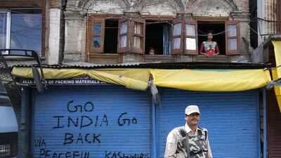 Kashmiris look from the windows of their house as an Indian Paramilitary officer stands guard during restrictions in downtown area of Srinagar, the summer capital of Indian Kashmir. Farooq Khan / EPA