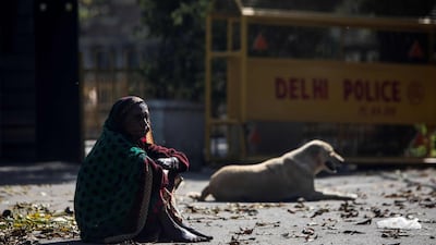 A woman sits next to a dog on a deserted street during the first day of a 21-day government-imposed nationwide lockdown in New Delhi. AFP