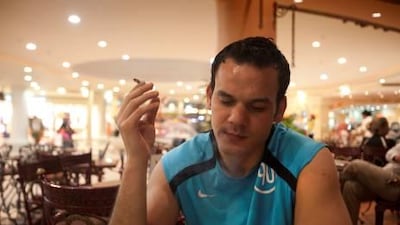 Houssem Bouzidi, 28, from Tunisia, enjoys what wuthorities hope will be one of his last cigarettes at a local mall.