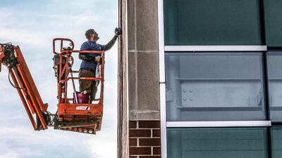 Andreas Richardson with The Window Guys works on a lift while cleaning the exterior windows of the Boardwalk Pipelines in Owensboro, Kentucky. The Messenger-Inquirer via AP