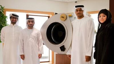 From left, Mohammed bin Neshooq, Ahmed Abdelrazzaq Abdullah, Khalif Sultan Zowayed and Amel Abdulla Amin, of the Emirates Institute for Advanced Science and Technology with a model of DubaiSat-2. Razan Alzayani / The National