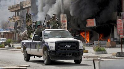 Members of Hashid Shaabi forces ride through Al Qadisiya neighborhood, north of Tikrit, as smoke rises from shops on April 3, 2015. Reuters