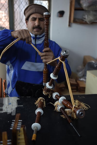 A Pakistani worker fixes a component to make a set of bagpipes at the Mid East bagpipe factory. AFP.