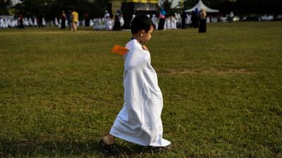 A Malaysian boy from the Little Caliphs kindergarten goes in search for a drink of water as other pupils (background) circumambulate a mockup of the Kaaba.