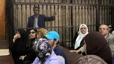 Tawfiq Okasha, a popular Egyptian TV presenter accused of inciting the killing of the country's new president on air, stands in the defendants' cage at the opening of his trial in Cairo, Egypt. Mohammed Assad / AP Photo