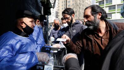 People queue in line to receive packages for precautions against coronavirus by the Basij, a militia loyal to Iran's Islamic republic establishment, from a booth outside Meydane Valiasr metro station in the capital Tehran, March 15. AFP