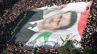 A giant portrait of the Syrian president, Bashar Al Assad, is carried by thousands of demonstrators in Damascus yesterday. The rally was to protest against the Arab League’s decision to impose crippling sanctions on Mr Al Assad’s regime.