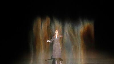 A gallery employee stands in the rainbow colours of the installation 'Beauty' where fine sprayed water is poured down and illuminated by a light, as part of the exhibition Olafur Eliasson: 'In real life' at the Tate Modern Gallery in London. Photo: AP