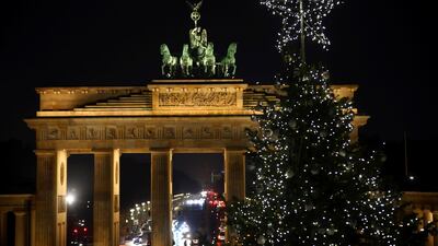 A Christmas tree is illuminated in front of Brandenburg Gate in Berlin, Germany. Reuters