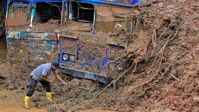 A worker digs buses out of the mud after a landslide triggered by Cyclone Ditwah, in Maspanna, Sri Lanka. AFP