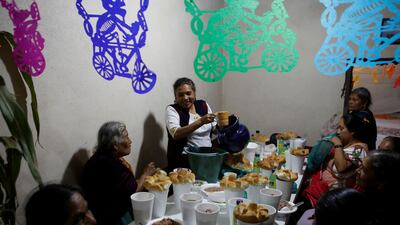 A woman serves food for her guests near an altar in homage to a person who died recently during the annual Day of the Dead celebration in Santa Fe de La Laguna in Mexico. Reuters