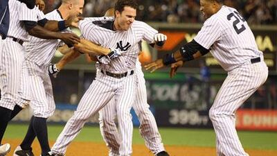 Jayson Nix is mobbed by fellow Yankees after hitting a game-winning single. Mike Stobe / Getty Images / AFP