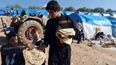 A young Syrian distributes bread in the refugee camp of Qah, in the northwestern Syrian province of Idlib.