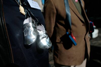 People with baby shoes tied with black ribbons around their neck to symbolize the children who died in homes where children were exiled for the shame of having been born to unwed mothers. PA via AP