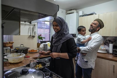 Anam Raza prepares the iftar meal while her husband Ahmed holds their son Daud, at their home in London, on May 08, 2020. Getty