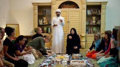 Suqrat Bin Bisher and Aisha Bishr explain the traditions of Iftar to expats who are having their first Iftar at Fatima Bisher's (not shown) home in Al Rams, Ras Al Khaimah. Razan Alzayani / The National