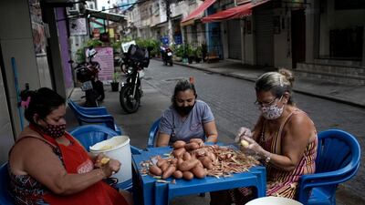 Women peel potatoes outside a snack bar amid the new coronavirus pandemic in Rio de Janeiro, Brazil, October 9, 2020. Silvia Izquierdo / AP