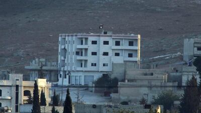 In this image shot with an extreme telephoto lens from the outskirts of Suruc at the Turkey-Syria border, ISIL's trademark black flag is seen atop of a building at the eastern end of the town of Kobani, Syria, on Monday. Lefteris Pitarakis / AP Photo
