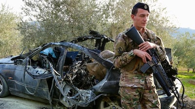 A soldier stands guard by the wreckage of a car hit by an Israeli drone in southern Lebanon. EPA