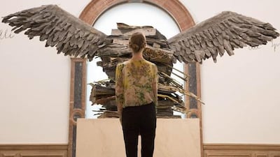 A gallery assistant poses for photographers with Language of the Birds (Sprache der Vogel) by artist Anslem Kiefer at a retrospective of his work at the Royal Academy of Arts in London September 23, 2014. Reuters