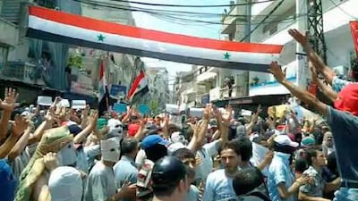 A grab made on Monday from a handout video made available by Shaam News Network on its Youtube channel, shows Syrians waving a national flag in Latakia, Syria. According to media reports, two women and two children were shot dead by security forces on Monday as troops intensified their operations in the eastern Syrian city of Deir al-Zour for the second day.