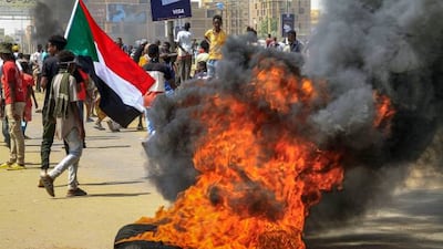 Protesters walk past burning tyres during an anti-military demonstration in Sudan's capital Khartoum. AFP
