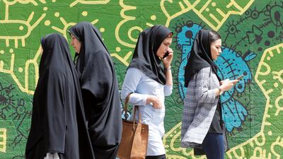 Iranians using their cell phones as they walk past a wall painting in Tehran on April 28, 2018. Abedin Taherkenareh / EPA