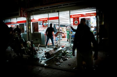 People stand in front of a shop that was plundered during the riots in Stuttgart. AFP
