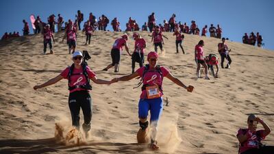 Women run down a sand dune as they take part in the desert trek "Rose Trip Maroc" in the erg Chebbi near Merzouga. AFP
