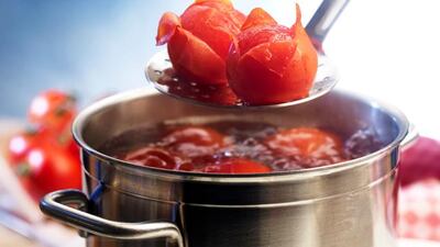 Tomatoes being blanched in boiling water --- Image by © Rose, Ludger/the food passionates/Corbis