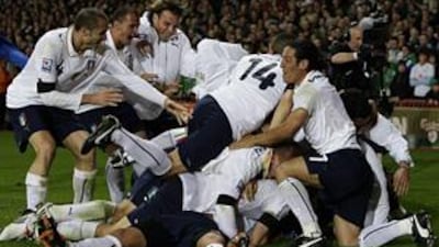 Italy's players pile on top of Alberto Gilardino, whose last-minute equaliser against Irerland in Dublin saw them qualify for the World Cup.