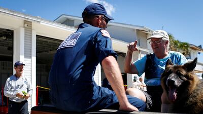 Andy Sherwood talks with a US Coast Guard officer as he is being evacuated from the island with his dog. Reuters