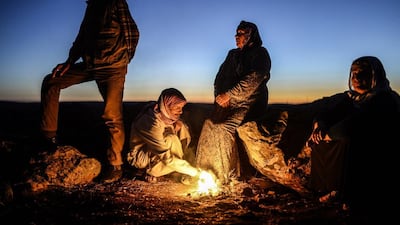 Kurdish woman Ghazal Daban, whose son is fighting in the Syrian town of Kobane also known as Ain al-Arab, gathers with Kurdish men around a bonfire in the southeastern Turkish village of Mursitpinar in the Sanliurfa province. Kurdish defenders of the strategic Syrian border town of Kobane awaited reinforcements after weathering another onslaught by Islamic State jihadists. Bulent Kilic / AFP