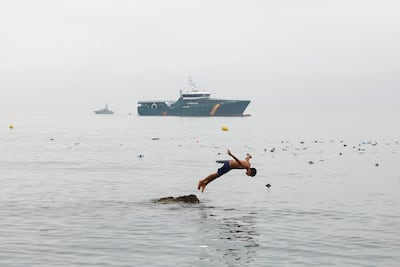 A young man from Morocco dives into the water near Ceuta with a Spanish civil guard vessel in the background. Reuters