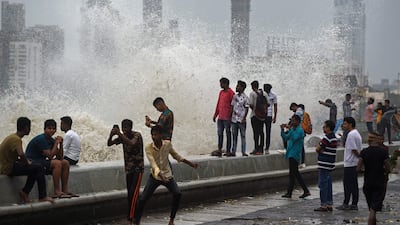 People enjoying high tides splashing on the sea front in Mumbai. AFP