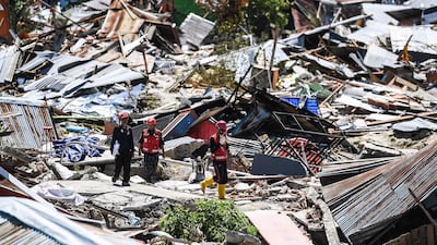 Rescuers walk past debris at Perumnas Balaroa village in Palu on October 5, 2018. AFP