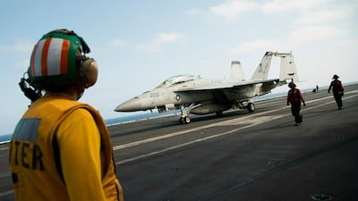 A crew member looks at an F/A-18 fighter jet on the deck of the USS Abraham Lincoln aircraft carrier in the Arabian Gulf. AP Photo