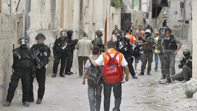Palestinian school children walk past Israeli riot police during clashes with masked youths on September 22, 2010. AFP Photo