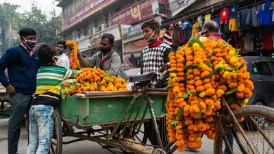 A vendor (C) selling marigold flowers for Diwali, the Hindu Festival of Lights, attends customers in a market area in New Delhi on November 14, 2020. / AFP / Jewel SAMAD