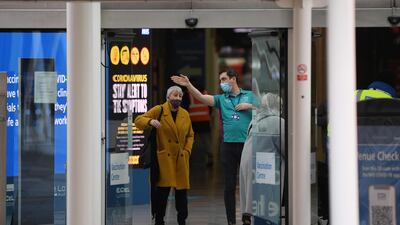 An NHS volunteer directs a woman at the door of the Covid-19 vaccination centre at ExCel London. AFP