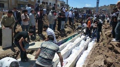 People watch a mass burial of more than 100 Sunni villagers killed in the central Syrian city of Houla in a massacre condemned globally.