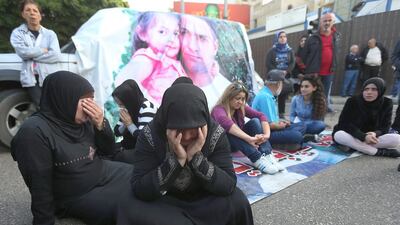 Families of Lebanese security forces who were kidnapped by Islamist militants block a main road during a protest after an Al Qaeda-linked group in Syria claimed it has killed kidnapped police officer Ali Bazzal, seen in poster with his daughter, in Beirut on December 6. Hussein Malla / AP Photo
