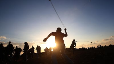 Palestinian protesters use slingshots to hurl stones during a demonstration near the border between Israel and Khan Yunis in the southern Gaza Strip. AFP