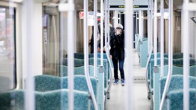 A woman holds her scarf in front of her mouth in an almost deserted suburban train in Berlin. AP