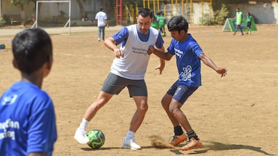 Former Spain international midfielder Xavi plays with Indian children a football game in Mumbai.