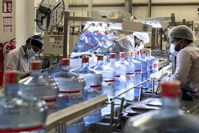 Workers inspect a line of freshly-filled five-gallon water bottles at the Mai Dubai factory. Antonie Robertson/The National
